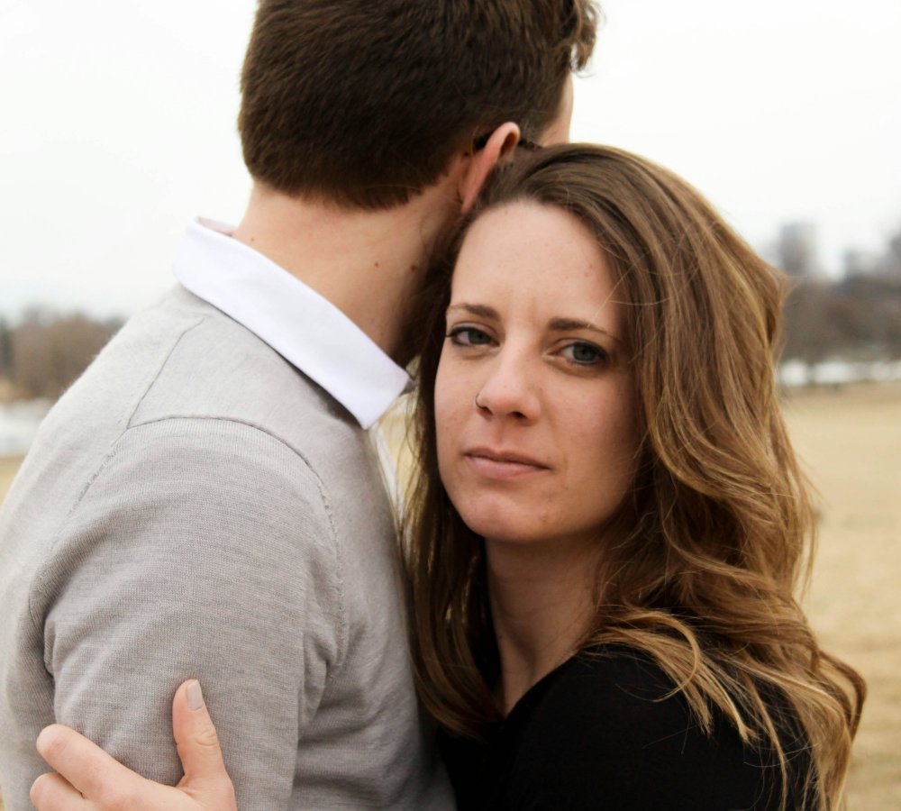 couple hugging, woman looking serious