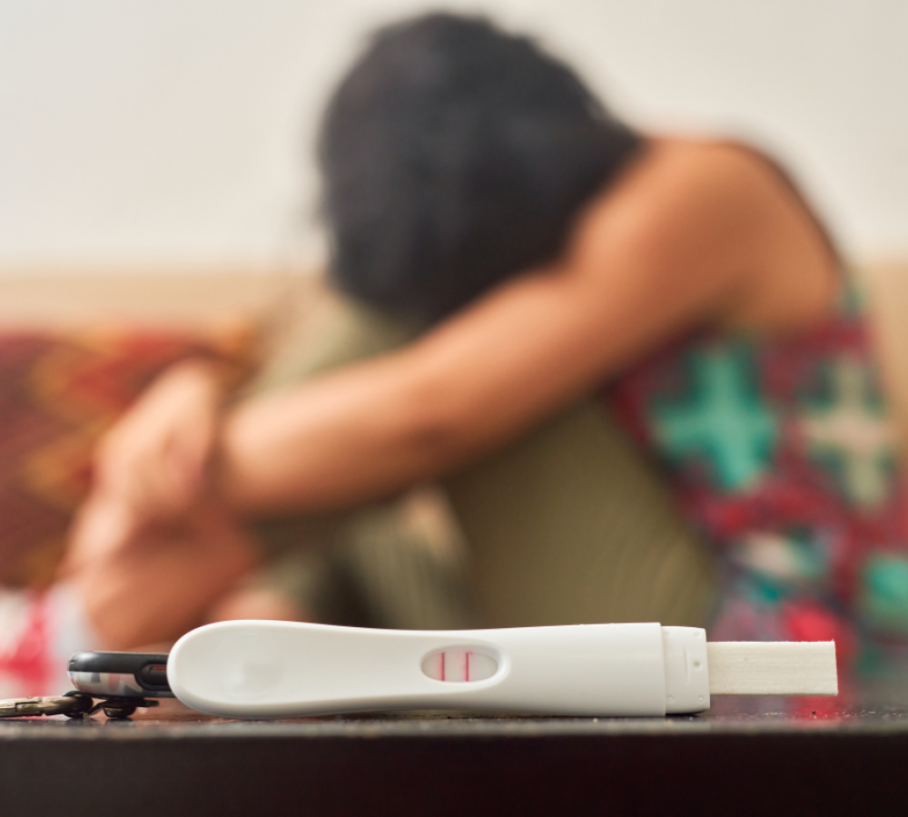 positive pregnancy test and sad woman