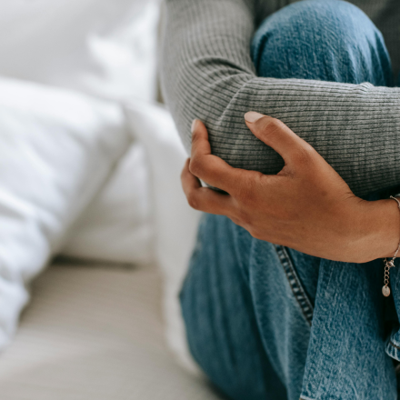 woman sitting alone holding her legs worried about unplanned pregnancy